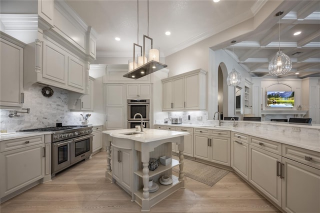 kitchen featuring light stone counters, decorative light fixtures, stainless steel appliances, and a center island with sink