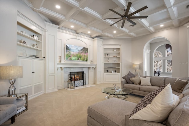 carpeted living room with built in shelves, ceiling fan, coffered ceiling, and beamed ceiling