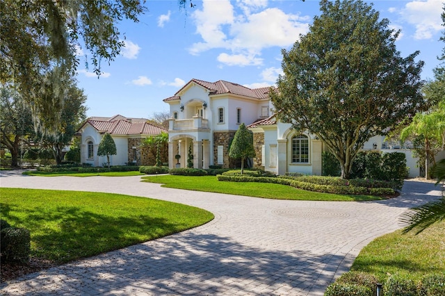 mediterranean / spanish house with a balcony and a front yard