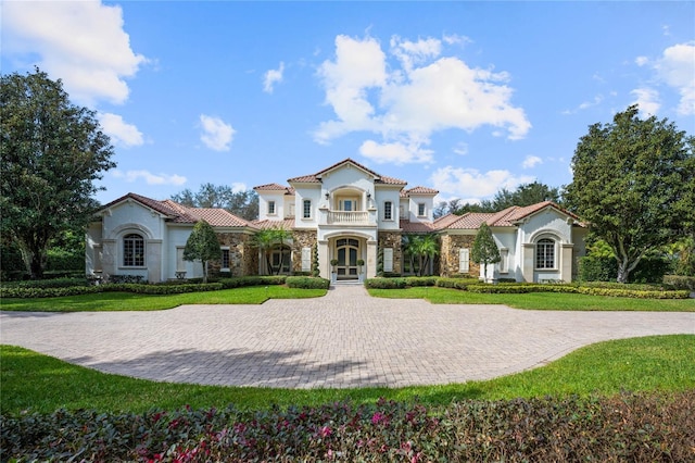 mediterranean / spanish house with french doors, a balcony, and a front yard