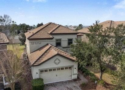 1494 Moon Valley Dr, Davenport, FL 33896 - view of front of house with a tiled roof, an attached garage, driveway, and stucco siding