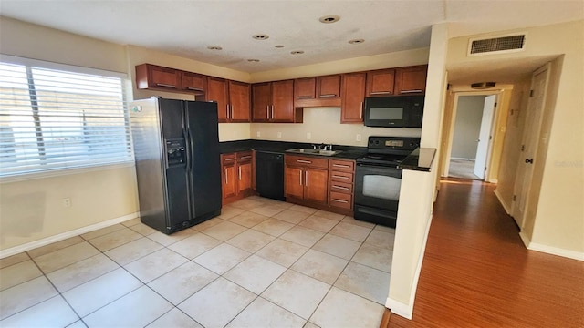 kitchen featuring sink, light tile patterned floors, and black appliances