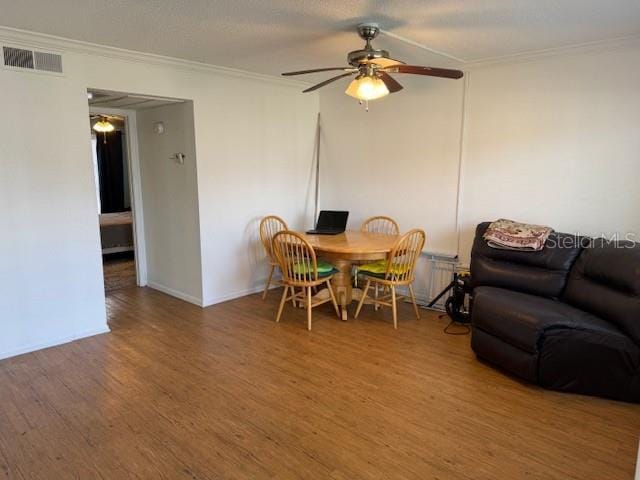 dining area with ceiling fan, wood finished floors, visible vents, and crown molding