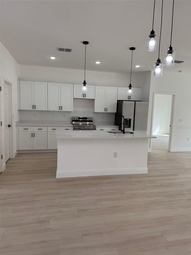 kitchen featuring decorative light fixtures, stainless steel appliances, light hardwood / wood-style floors, and white cabinets