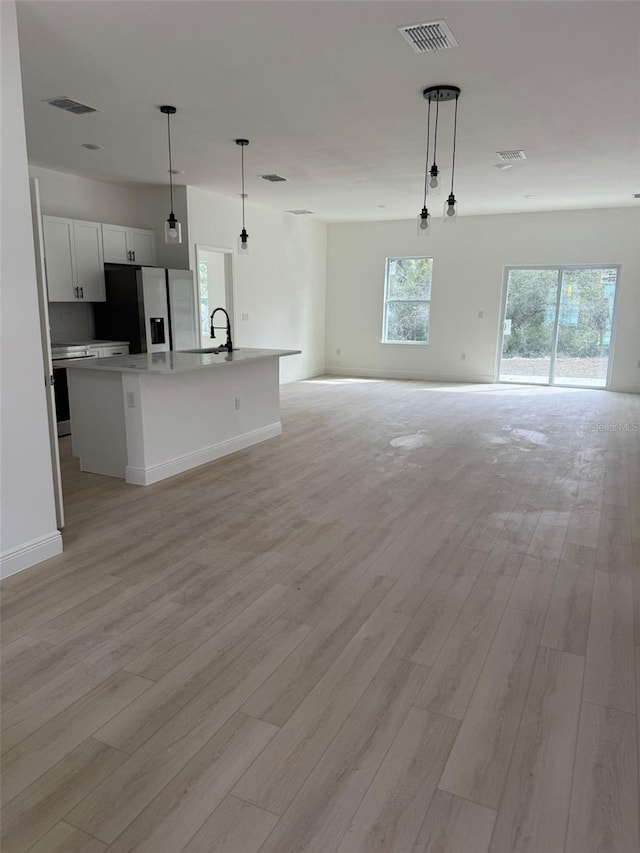 unfurnished living room with sink and light hardwood / wood-style flooring