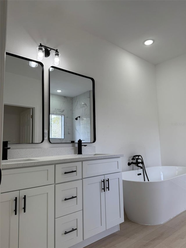 bathroom with hardwood / wood-style flooring, vanity, and plus walk in shower