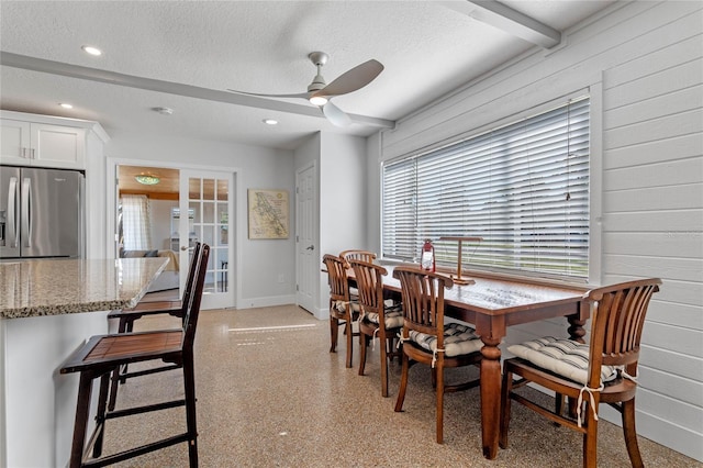 dining space featuring ceiling fan, beam ceiling, french doors, and a textured ceiling