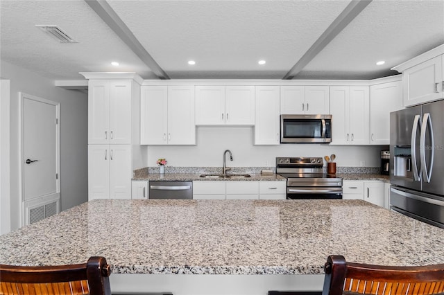 kitchen with stainless steel appliances, a kitchen bar, a center island, and sink