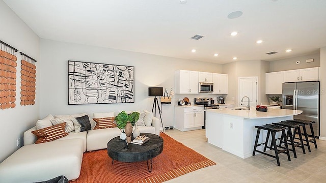 kitchen featuring sink, a breakfast bar area, white cabinetry, stainless steel appliances, and a center island with sink