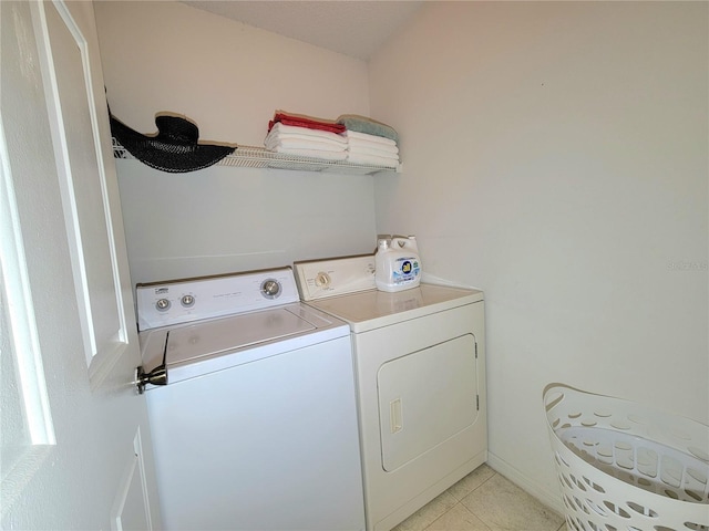 clothes washing area with washing machine and clothes dryer and light tile patterned floors