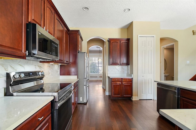 kitchen with tasteful backsplash, dark hardwood / wood-style flooring, light stone counters, stainless steel appliances, and a textured ceiling