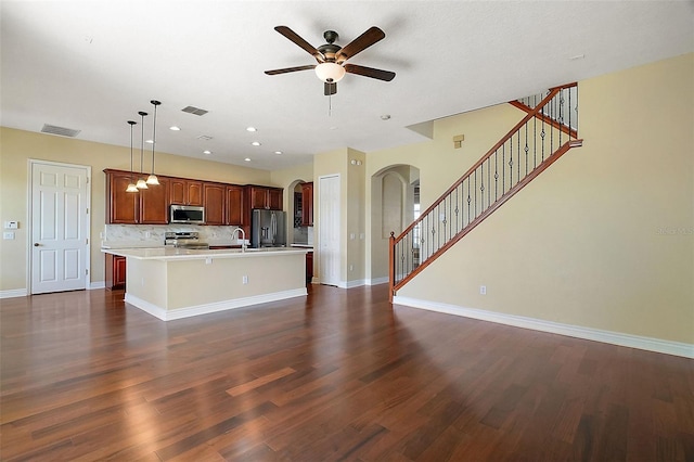 kitchen with an island with sink, appliances with stainless steel finishes, dark hardwood / wood-style floors, and decorative light fixtures