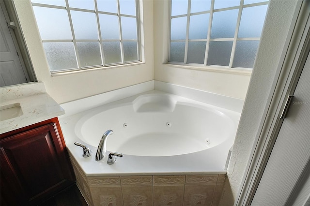 bathroom featuring a relaxing tiled tub and vanity