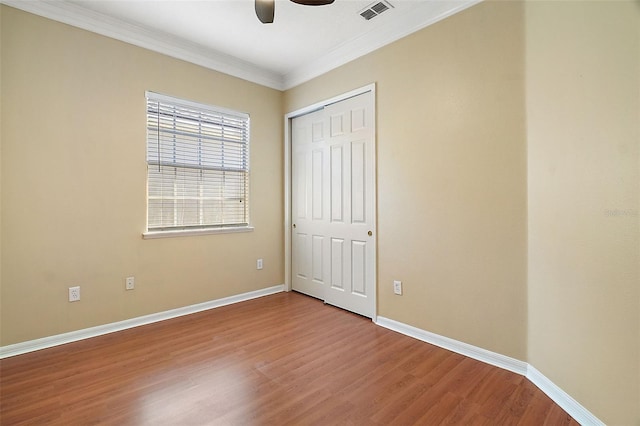 unfurnished bedroom featuring crown molding, hardwood / wood-style floors, ceiling fan, and a closet