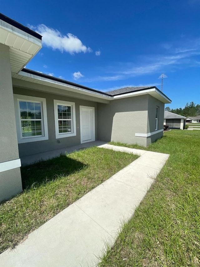 property entrance featuring a yard and stucco siding