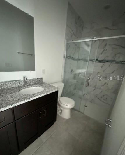 full bath with toilet, a marble finish shower, and vanity