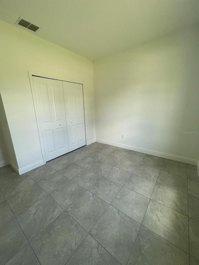 unfurnished bedroom featuring a closet, visible vents, and baseboards