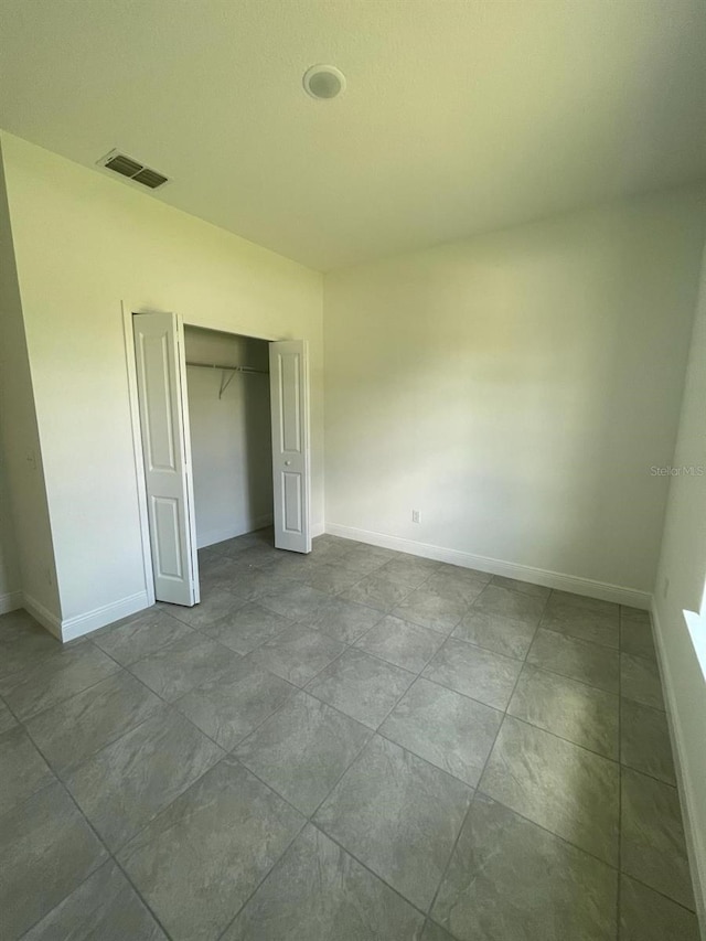 unfurnished bedroom with a closet, visible vents, and baseboards