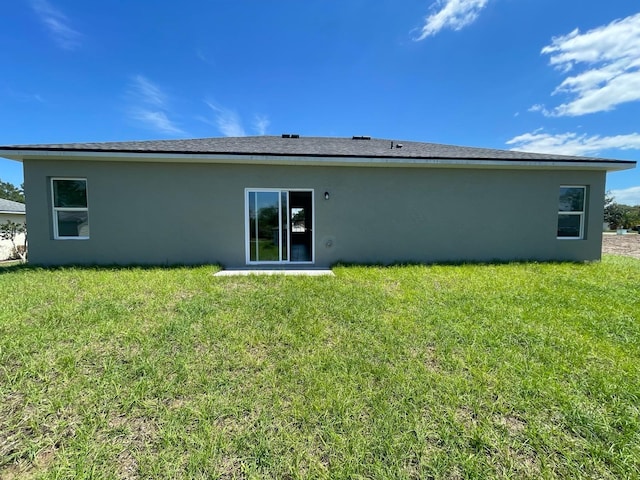 back of property featuring a lawn and stucco siding