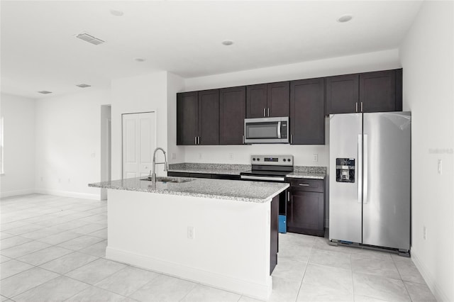 3268 W Montgomery Ln, Citrus Springs, FL 34433 - kitchen with stainless steel appliances, a center island with sink, dark brown cabinetry, light stone counters, and light tile patterned floors