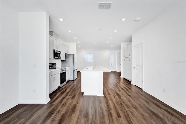 kitchen featuring visible vents, a kitchen island with sink, stainless steel appliances, light countertops, and a sink