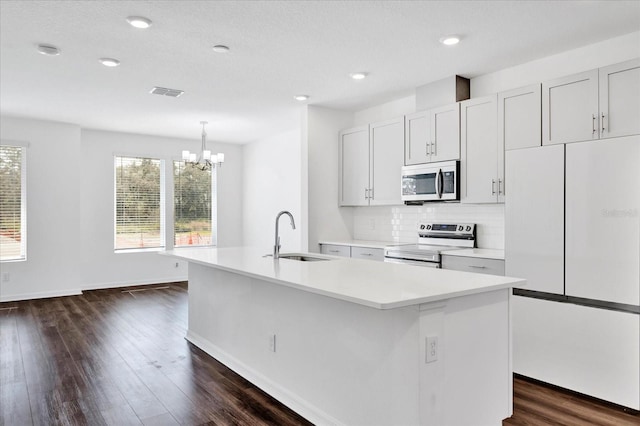 kitchen with light countertops, appliances with stainless steel finishes, a sink, and a center island with sink