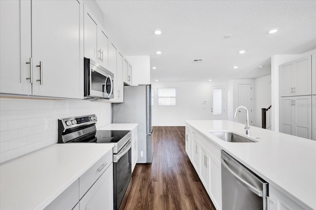 kitchen with stainless steel appliances, sink, dark wood-type flooring, and white cabinets