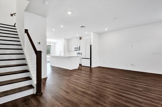 unfurnished living room with baseboards, visible vents, dark wood-style floors, stairs, and recessed lighting