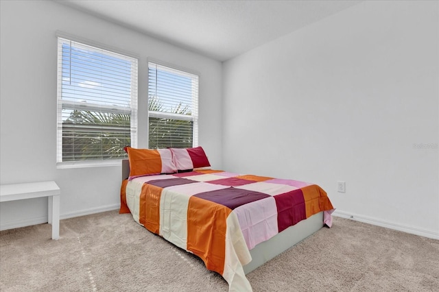 bedroom with baseboards and light colored carpet