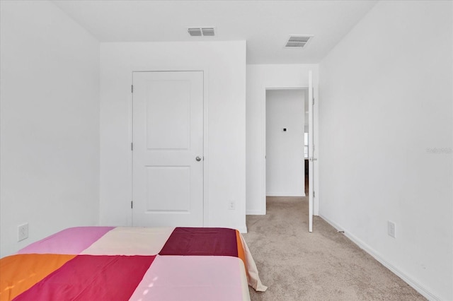 unfurnished bedroom featuring light carpet, visible vents, and baseboards