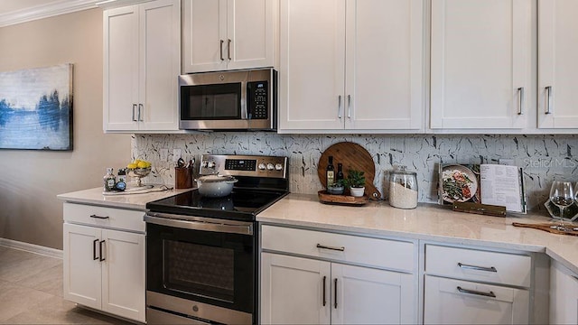 kitchen with crown molding, white cabinetry, stainless steel appliances, light stone counters, and tasteful backsplash