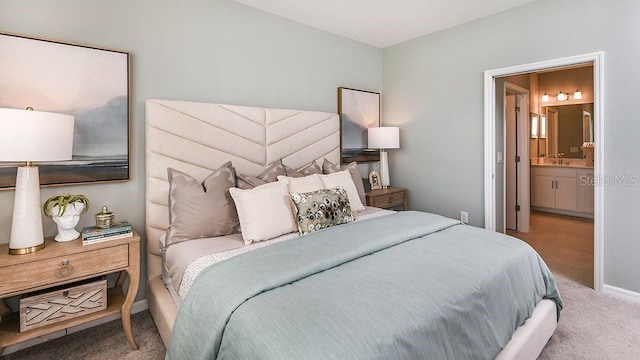 carpeted bedroom featuring connected bathroom and sink