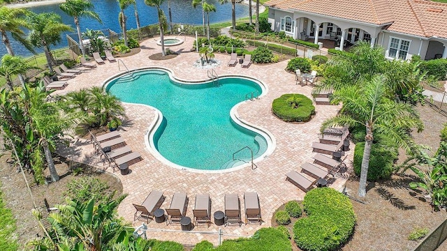 view of pool with a hot tub, a patio, and a water view