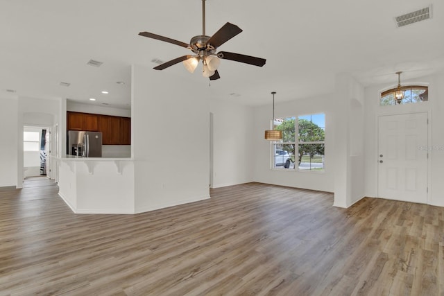 unfurnished living room with plenty of natural light, ceiling fan, and light hardwood / wood-style flooring