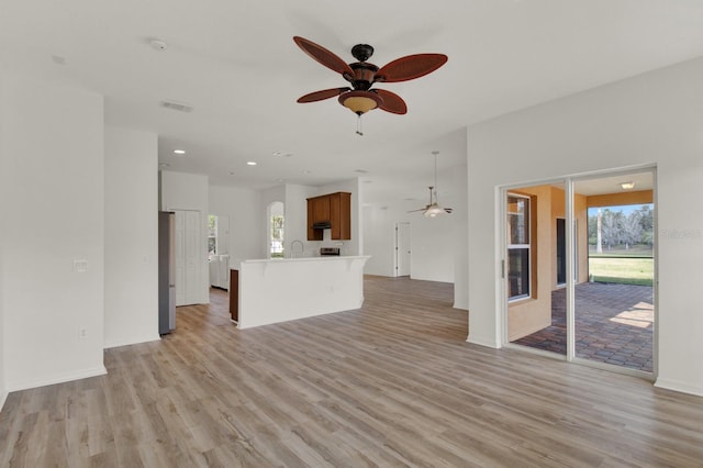 unfurnished living room with ceiling fan, light hardwood / wood-style flooring, and a healthy amount of sunlight