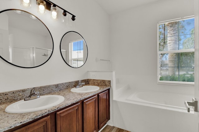 bathroom featuring independent shower and bath, vanity, and a healthy amount of sunlight