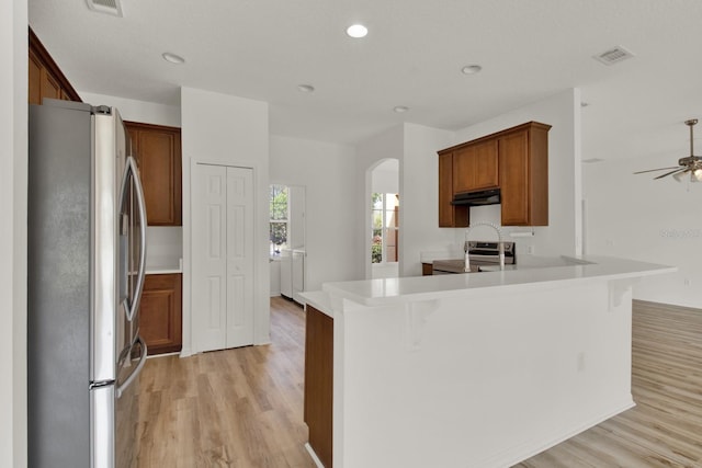 kitchen featuring a breakfast bar area, light hardwood / wood-style flooring, appliances with stainless steel finishes, kitchen peninsula, and ceiling fan