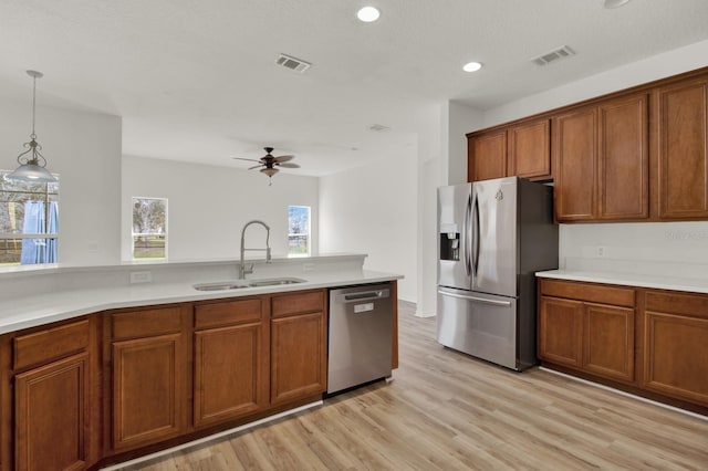 kitchen featuring sink, light hardwood / wood-style flooring, ceiling fan, hanging light fixtures, and stainless steel appliances