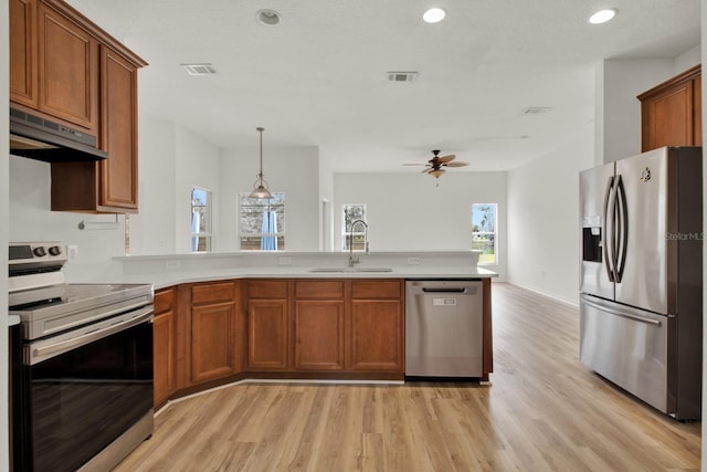 kitchen featuring appliances with stainless steel finishes, decorative light fixtures, sink, light hardwood / wood-style floors, and kitchen peninsula