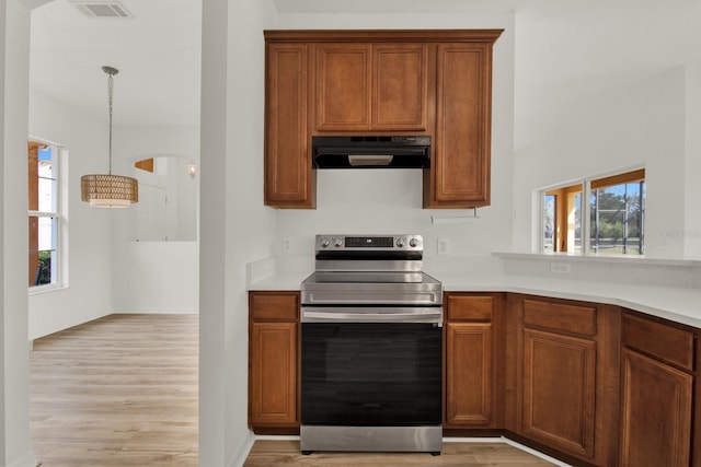 kitchen featuring stainless steel electric range oven, ventilation hood, hanging light fixtures, and light hardwood / wood-style flooring