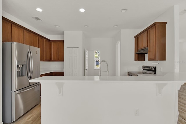 kitchen featuring sink, a kitchen breakfast bar, kitchen peninsula, stainless steel appliances, and light hardwood / wood-style floors