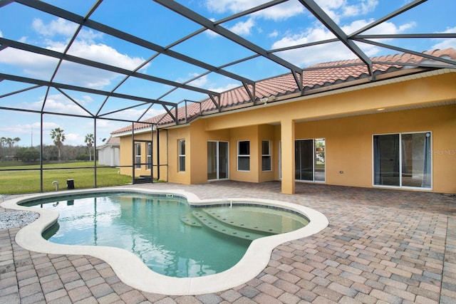 view of pool with a yard, glass enclosure, and a patio area