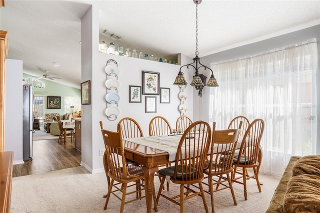 carpeted dining room with lofted ceiling, a textured ceiling, visible vents, and a healthy amount of sunlight