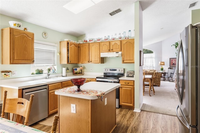 kitchen with visible vents, appliances with stainless steel finishes, a center island, light countertops, and under cabinet range hood