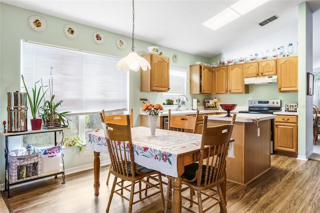 kitchen with decorative light fixtures, visible vents, light countertops, stainless steel range with electric stovetop, and under cabinet range hood