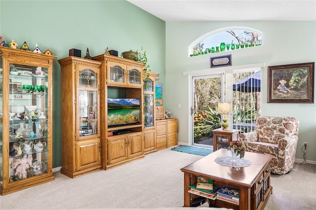 living room with baseboards, lofted ceiling, and light colored carpet