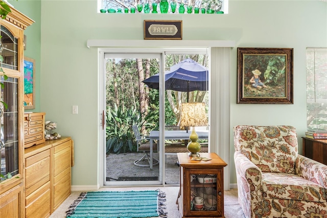 doorway featuring plenty of natural light, baseboards, and light colored carpet