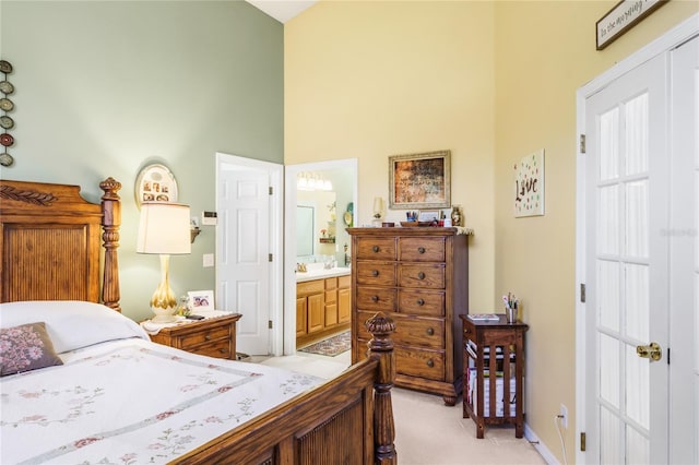 bedroom featuring a towering ceiling, ensuite bath, a closet, and light colored carpet