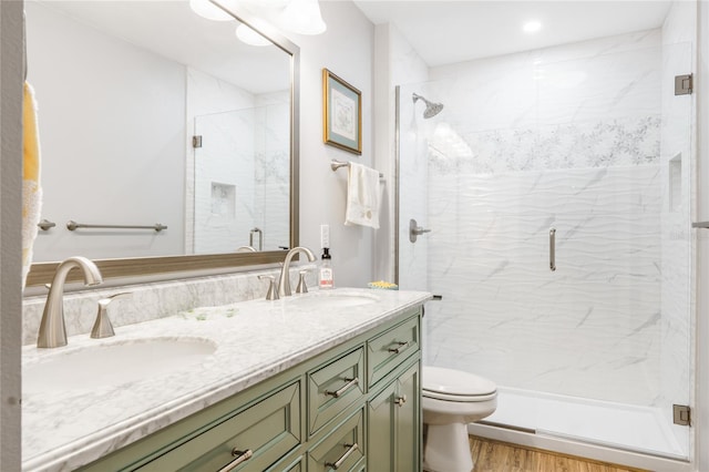 full bathroom featuring a stall shower, wood finished floors, a sink, and double vanity