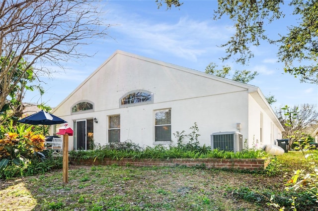 rear view of house featuring cooling unit and stucco siding